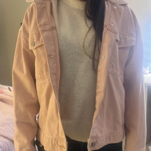 Ljusrosa jeansjacka med knappar - ( har en pytteliten fläck vid ärmen som jag aldrig prövat tvätta bort så jag knappt har haft på den!) Säljer en snygg ljusrosa jeansjacka med klassisk krage och två bröstfickor med lock och silverfärgade knappar. Jackan har en loose passform och är tillverkad i mjukt bomullsmaterial. Perfekt att slänga på över en hoodie eller t-shirt för en chill look.