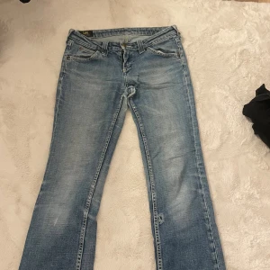Ljusblå bootcut jeans från Lee - Snygga ljusblå jeans från Lee med klassisk femficksdesign och bootcut-ben. Jeansen har slitningar och men det kan man laga, säljer därför billigare. Passar nån runt 165.