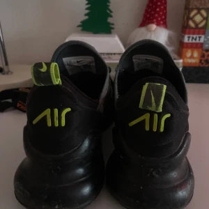 Nike Air Max 270 sneakers grå/gul - Nike Air Max 270 sneakers i grått med neon-gula detaljer och logga. Skorna har en ventilerande mesh-överdel, snörning och en kraftig plattformssula med Air Max-dämpning. Snygg sportig look med rund tå och coola färgkontraster.