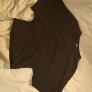 Svart croppad topp från Gina Tricot - En svart croppad topp från Gina Tricot i enkel och stilren design. Toppen har rund halsringning och korta ärmar, perfekt att matcha med jeans eller kjol. Tillverkad i mjuk bomull för en bekväm känsla.