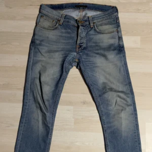 Blå jeans från Nudie Jeans  - Säljer dessa asfeta vintage Nudie Jeans i fint skick. Har använt dessa i mer än ett år och tvättat dem en gång. Jeansen har en snygg wash och ett pyttelitet hål vid bengrenen, men inget som man tänker på. Storleken är W29/L30 och modellen är Grim Tim (slim fit). Skriv gärna vid minsta fråga, pris kan diskuteras.