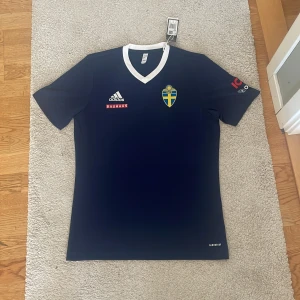 Svensk blå fotbollströja Adidas M - Säljer en Sverige tränings tröja i storlek M, helt oanvänd och är i bra kvalité 