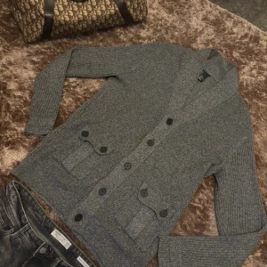 Grå kofta med knappar - Snygg grå Cardigan/Kofta med knappar framtill och två fickor. Perfekt för lager-på-lager speciellt nu på vintern. Den har en klassisk design är i skick 9/10, inte använd mer än 3 gånger. Hör av vid fler frågor