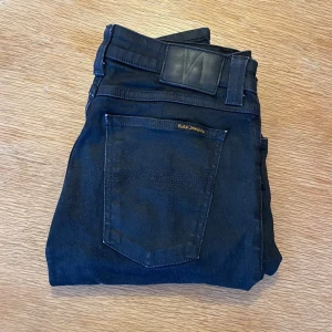 Nudie Jeans - Svarta jeans från Nudie med klassisk femficksdesign. Jeansen är tillverkade i stretchigt material och har svarta sömmar, knapp och dragkedja i gylfen. Perfekt för dig som gillar en clean och stilren look. Hör av er vid funderingar!💬✅