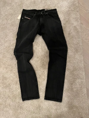 Svarta Diesel Belther  - Svarta jeans från Diesel, modell Belther, med slim fit och klassisk femficksdesign. Jeansen har svarta sömmar, knappgylf och diskret Diesel-logga på fickan. Materialet är stretchigt denim för skön passform och snygg siluett. Dom är så sjukt snygga men dom är tyväär alldeles för små för mig. Dom är aldrig använda fick inte ens på mig dom så dome helt oanvända. 