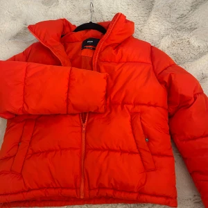 Röd pufferjacka från Bik Bok - Säljer en röd pufferjacka från Bik Bok i storlek S. Jackan har en schysst oversized look, hög krage och dragkedja framtill.❤️ Få gånger använd 