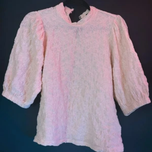 rosa blus med puffärm från Lindex - Säljer en söt rosa blus från Lindex i storlek S. Blusen har puffiga trekvartsärmar, hög hals och ett strukturerat tyg som ger en unik look. Perfekt för dig som gillar romantiska och trendiga detaljer.