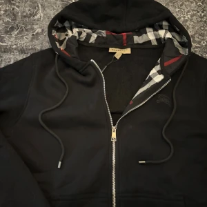 Burberry zip-up hoodie  - Snygg zip-up hoodie från Burberry. Stilren design med dragkedja och klassiska detaljer. Oanvänd och i fint skick. 