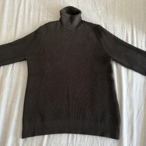 H&M Turtleneck - Svart stickad polotröja från H&M i regular fit. Tröjan har ribbad struktur, lång ärm och hög polokrage som ger en chill och stilren vibe. Perfekt för lager-på-lager och funkar fett bra till jeans eller cargo. Materialet är mjukt och håller värmen.