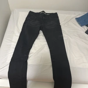 Svarta slim fit jeans från LAB Industries - Svarta jeans från LAB Industries i modellen Luke/Slim Fit. Jeansen har klassisk femficksdesign, diskreta slitningar framtill och smal passform. Tillverkade i stretchigt denim för extra komfort. Perfekta för dig som gillar en stilren och modern look.