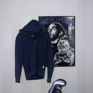 Mörkblå hoodie från Jack & Jones - Säljer en mörkblå hoodie från Jack & Jones Essentials i storlek S. Tröjan har huva med snörning, hel dragkedja framtill och ribbade muddar vid ärmslut och nederkant. Materialet är mjuk bomull och polyester, perfekt för chill dagar.