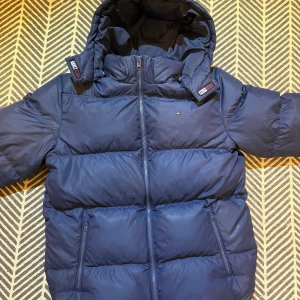 Marinblå pufferjacka från Tommy Hilfiger - Säljer en marinblå pufferjacka från Tommy Hilfiger. Perfekt för kalla dagar och riktigt stilren.