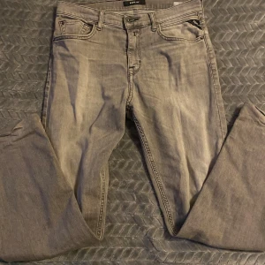 Replay grå jeans straight fit - Snygga grå jeans från Replay med klassisk femficksdesign och raka ben. Jeansen har svarta sömmar på bakfickorna och metallknapp framtill. Materialet är mjukt denim i bomull och passformen är normal med straight fit.