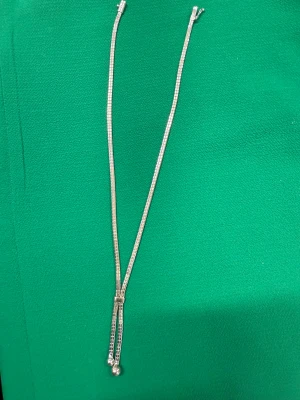 Silvrigt halsband med justerbar lås - Snyggt halsband i silverhalsband stämplat  med två smala kedjor som möts i en justerbar låsdel. Kedjorna har en fyrkantig länkdesign och avslutas med små kulor. Perfekt för dig som gillar stilrena och moderna accessoarer.