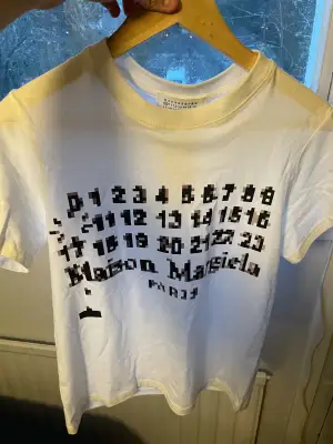 Helt oanvänd vit t-shirt från Maison Margiela med unikt svart pixelinspirerat tryck av siffror och logga på bröstet. Storlek S och passar dig som är 170-180 drygt. 