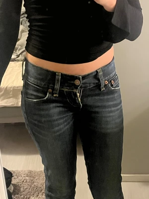 Levi's mörkblå jeans - Säljer ett par klassiska Levi's 501 jeans i mörkblå tvätt med snygga slitningar. Modellen har låg midja, och fem fickor. Jeansen är tillverkade i robust denim och har den ikoniska Levi's-lappen bak i midjan. Perfekt för dig som gillar tidlös stil.