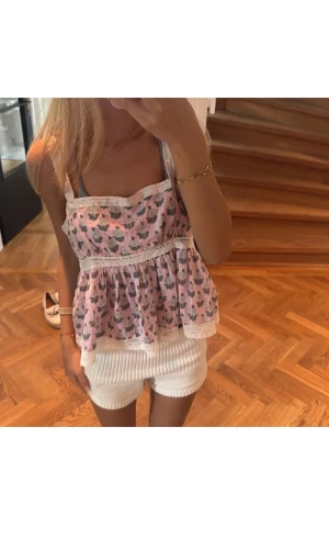 Rosa blommig linnetopp med spets - Jättesöt rosa linnetopp med blommigt mönster. Toppen har breda axelband, volangig och luftig passform samt fina spetsdetaljer. Använd fåtal gånger därav bra skick. Köptes på plick av Filippa Montan för 250 kr. Pris går att diskuteras. 