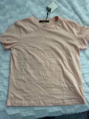 T-Shirt BikBok Korall/Aprikos - En fin t-shirt i en aprikos/korall färg, tröjan  är aldrig använd, är i perfekt skick och har prislappen på men den har tyvärr gått sönder, se bilden💕