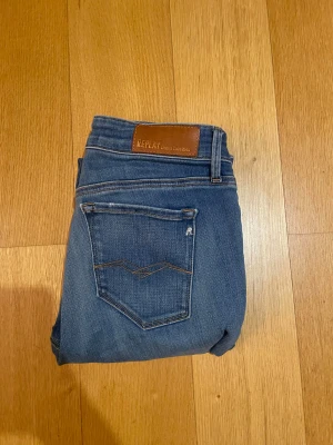 Replay  - Snygga blå jeans från Replay med klassisk femficksdesign och brunt läderpatch bak i midjan. Modellen är skinny med smal passform och raka ben. Jeansen har subtila slitningar och är tillverkade i mjukt jeansmaterial med stretch för extra komfort.