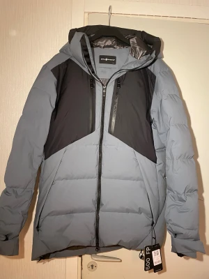 Sail Racing Patrol Down Jacket blå - Säljer en Sail Racing Patrol Down Jacket. Jackan är dunfodrad, har huva, två bröstfickor med dragkedja och en stilren design, perfekt för kalla dagar. Snygg och funktionell med modern look. Skriv vid frågor och kan sänka priset vid snabb affär