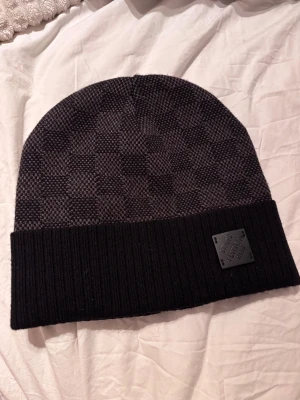 Rutig svart väst från Louis Vuitton - Pris kan diskuteras. Snygg svart väst från Louis Vuitton med diskret rutigt mönster och ribbad nederkant. Västen har en stilren form och är tillverkad i mjukt stickat material. Märkets logga sitter på en svart patch framtill för extra lyxig känsla.