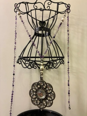 Statement halsband  - Unik statement halsband med tunna lila och transparenta pärlor, dekorerad med en stor rund brosch i antik silverfärg och glittriga stenar. Broschen har ett blommigt mönster och pärlorna ger en bohemisk vibe. Perfekt för dig som vill sticka ut med detaljer och glans.