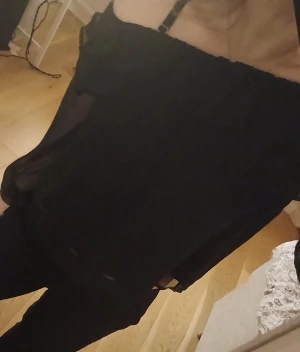 Svart offshoulder blus med volang - Säljer en marinblå offshoulder blus i tunn, luftig chiffong med volangdetaljer upptill. Blusen har vida ärmar och resår vid axlarna för en snygg passform. Perfekt för dig som gillar trendiga och stilrena plagg.