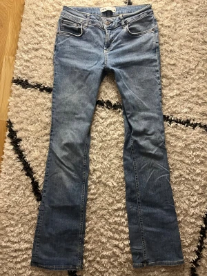Blå bootcut jeans från Zara - Snygga ljusblå jeans från Zara med klassisk femficksdesign, midwaist och bootcut-ben. Jeansen har normal passform och är tillverkade i mjukt denimtyg med subtila slitningar. Perfekt längd på benen om du är ca 170 cm lång 