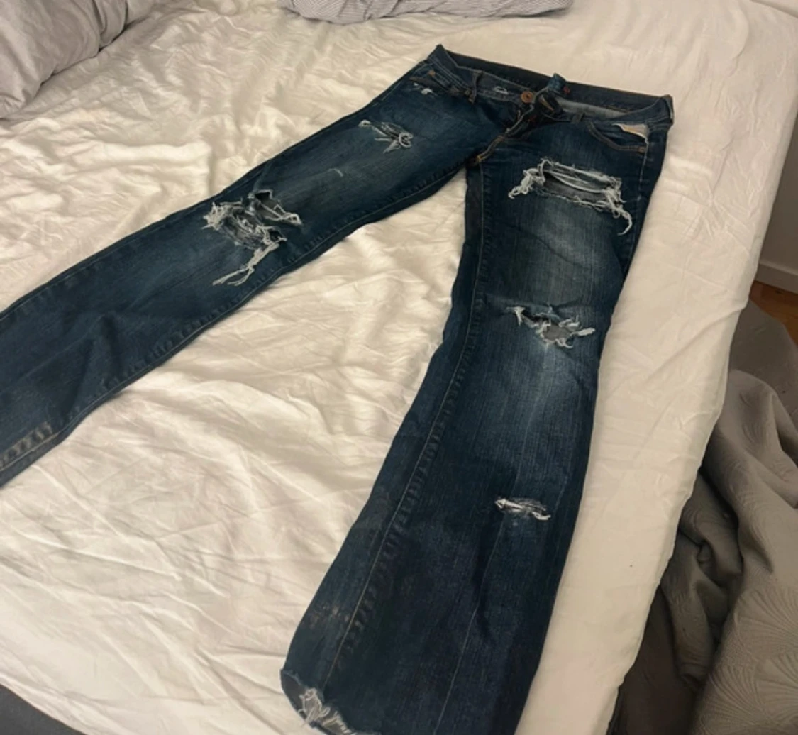 Blå slitna jeans med broderade fickor