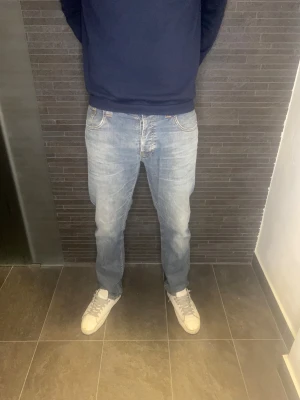 Nudie Jeans  - Säljer ett par ljusblå jeans från Nudie Jeans i klassisk femficksmodell. Nypris: ca 1800 Jeansen har orangea sömmar och snygga detaljer på bakfickorna. Jeansen är i mycket fint skick! 