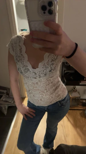 Vit spetsblus från ONLY - Supersnygg vit blus från ONLY i spets med v-ringad hals och korta ärmar. Blusen har ett detaljerat blommigt spetsmönster och är lätt transparent. Perfekt att styla med jeans eller kjol för en trendig look. Det står att det är stl XL men den sitter absolut inte som en XL utan mer som en S eller M, och toppen är riktigt feminin. 
