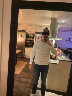 Vit Moncler Cardigan  - Säljer en snygg vit cardigan från Moncler med stickade ärmar och hög krage. Jackan har dragkedja framtill, två fickor med knapp och Moncler-logga på bröstet. Perfekt för dig som vill ha en stilren och fräsch look under kyliga dagar.                                                                        I ny skick ingen missfärgning eller defekt!  