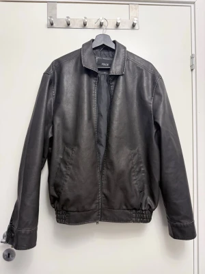 Svart skinnjacka från Xside, M - Svart skinnjacka från Xside i storlek M. Jackan har klassisk krage, dragkedja framtill och två sidofickor. Materialet är syntetiskt skinn med slät yta och insidan är fodrad.