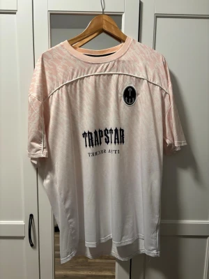 Rosa/Vit Trapstar T-shirt - Säljer en rosa och vit t-shirt från Trapstar i storlek XL. ENDAST TESTAD!!! Används ej därav till salu! Pm vid fler frågor! 