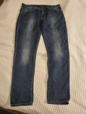 Blå jeans straight fit - Blå jeans från Chica london med klassisk straight fit.. Jeansen har fem fickor och en stjärndetalj på bakfickan. Tvättad look med ljusare partier.