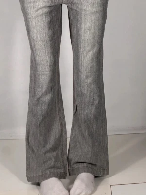 Grå bootcut jeans från Mango - Snygga grå jeans med bootcut passform och klassisk femficksdesign. Jeansen har en lågmidjad siluett och är tillverkade i ett mjukt bomullsmaterial med lätt tvättad look. Perfekt för dig som gillar retrovibbar och vill ha ett par jeans som sticker ut.