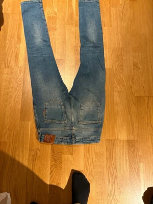 Blå skinny jeans från Scotch & Soda - Snygga blå jeans från Scotch & Soda i storlek 14. Modellen är skinny med smal passform och klassisk femficksdesign. Jeansen har ljusare tvättade partier och detaljerade sömmar. Materialet är jeans med en mjuk känsla och stretch för extra komfort.