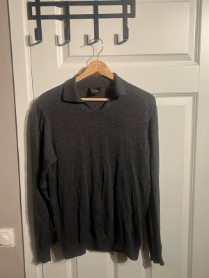 Mörkgrå pikétröja från Oscar Jacobson - Snygg mörkgrå pikétröja från Oscar Jacobson i mjukt material. Om du har mer frågor eller vill se mer bilder är det bara att fråga