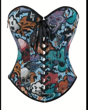 Färgglad korsett med grafiskt mönster - Säljer en unik korsett med grafiskt och tecknat mönster i blått, svart, orange, lila och vitt. Korsetten har snörning framtill och baktill, samt dragkedja på sidan. Modellen är axelbandslös och har svarta kantband. Perfekt för dig som vill sticka ut. Eller kanske till någon temafest.