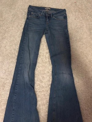 Blå bootcut jeans från gina tricot perfect jeans - Snygga blå jeans från gina tricot perfect jeans i storlek 36. Modellen har klassisk femficksdesign och bootcut-ben som ger en schysst retrovibe. Jeansen är tillverkade i jeansmaterial med en cool tvätt och kontrastsömmar. Perfekt för dig som gillar lite bredare ben.