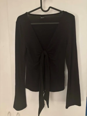 Svart omlottopp från Gina Tricot🫶🏻 - Säljer en svart omlottopp från Gina Tricot i storlek S. Toppen har lång ärm, djup v-ringning och snygg knytning framtill. Materialet är mjukt och stretchigt, perfekt för att styla med jeans eller kjol. Enkel och stilren design. Jätte söt!🤍