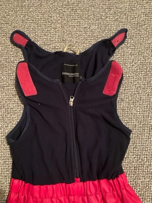 Didriksons täckbyxor röd/svart Galon - Täckbyxor från Didriksons i rött och svart med reflexdetaljer vid bensluten. Byxorna har hängslen med kardborre, dragkedja framtill och förstärkta knän. Materialet är Galon, perfekt för blöta dagar. Snygg och funktionell design med logga på benet. Barnstorlek 130