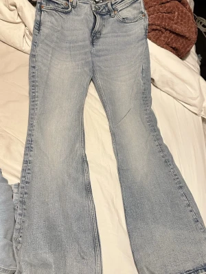 Bootcut jeans i ljusblå denim från weekday  - Säljer ett par bootcut jeans från Flame i ljusblå tvättad denim. Klassisk femficksmodell med dragkedja och knapp framtill. Jeansen har breda ben och snygga slitningar för en chill vibe. Perfekt för dig som gillar retrostil och vill sticka ut.
