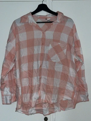 Rutig rosa och vit skjorta - Säljer en oversized skjorta med stora rutor i rosa och vitt. Skjortan har klassisk krage, knappstängning framtill och en bröstficka. Materialet känns lätt och luftigt, perfekt för dig som gillar avslappnad stil. Använd ett par gånger när jag sovit och är från H&M