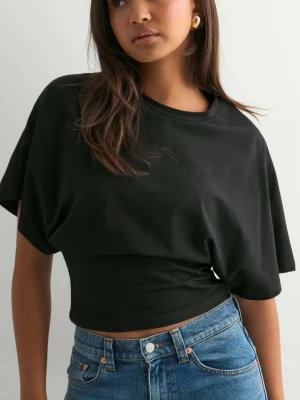 Svart croppad t-shirt - Snygg svart croppad t-shirt med korta ärmar och avslappnad passform. Perfekt till jeans eller kjol för en chill och trendig look. Gjord i mjukt bomullstyg som känns skönt mot huden. Nästan oanvänd, köpt för 250kr 