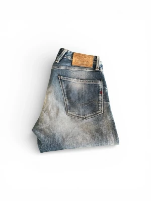 Replay blå jeans  - Säljer ett par snygga Replay jeans i klassisk blå tvätt med slitna detaljer och raka ben. Jeansen har fem fickor, tydliga kontrastsömmar och Replay-logga på insidan. Materialet är robust denim och passformen är normal. Perfekt för dig som gillar en cool och avslappnad stil. Måtten är 100cm längd och 42cm bredd