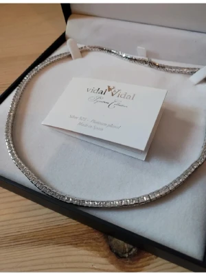 Silverfärgad platina-pläterad halskedja Vidal & Vidal - Snygg och stilren halskedja från Vidal & Vidal Signature Collection, tillverkad i 925 sterling silver och pläterad med platina. Kedjan har ett glittrigt utseende med fyrkantiga länkar som ger en lyxig vibe. Perfekt för att lyfta din outfit med lite extra bling. Aldrig använd. 