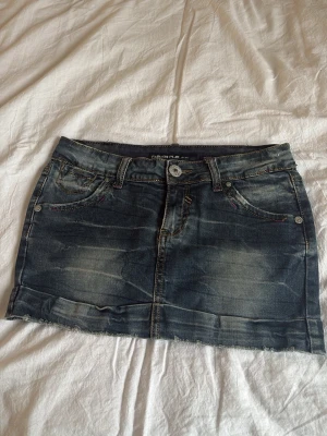 Mörk jeanskjol från Fashion Play - Säljer en snygg mörkblå jeanskjol från Fashion Play med slitna detaljer och rå kant nedtill. Kjolen har klassiska fickor både fram och bak, samt synliga sömmar i kontrastfärg💕