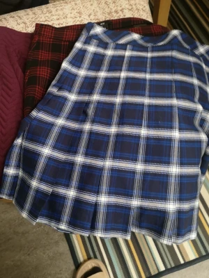 Kjol paket med Tre snygga kjolar från H&M Divided - Säljer tre kjolar i storlek S från H&M Divided. En vinröd kjol med quiltad struktur och dragkedja i sidan, en blå och vit rutig kjol med plisserad design samt en svart och röd rutig kjol med klassiskt rutmönster. Perfekt för dig som gillar att mixa stilar och färger.