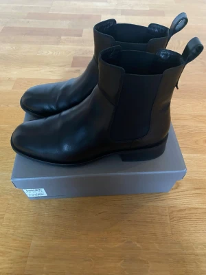 Svarta boots från Vagabond - Säljer ett par stilrena svarta boots från Vagabond i skinn. Bootsens klassiska design har elastiska paneler på sidorna och en rund tå. Perfekt för dig som gillar minimalistisk look och vill ha ett par boots som funkar till många outfits.